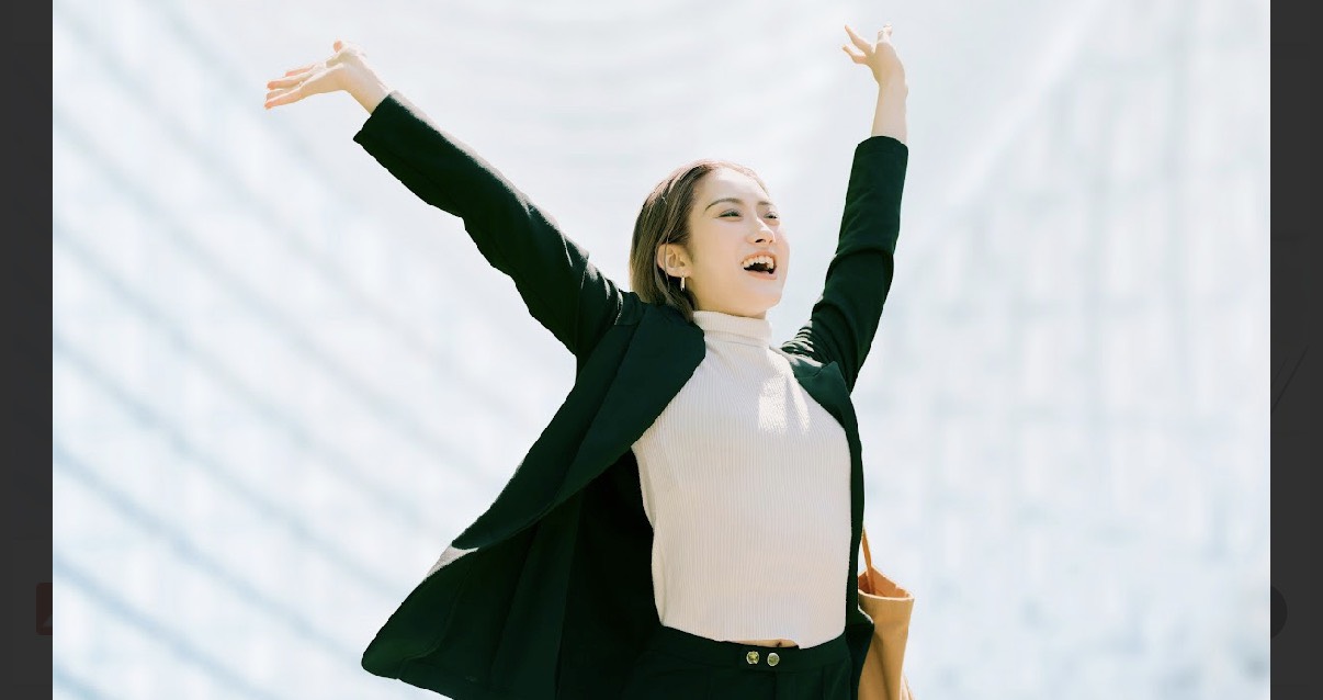 青空の下で両手を広げる女性